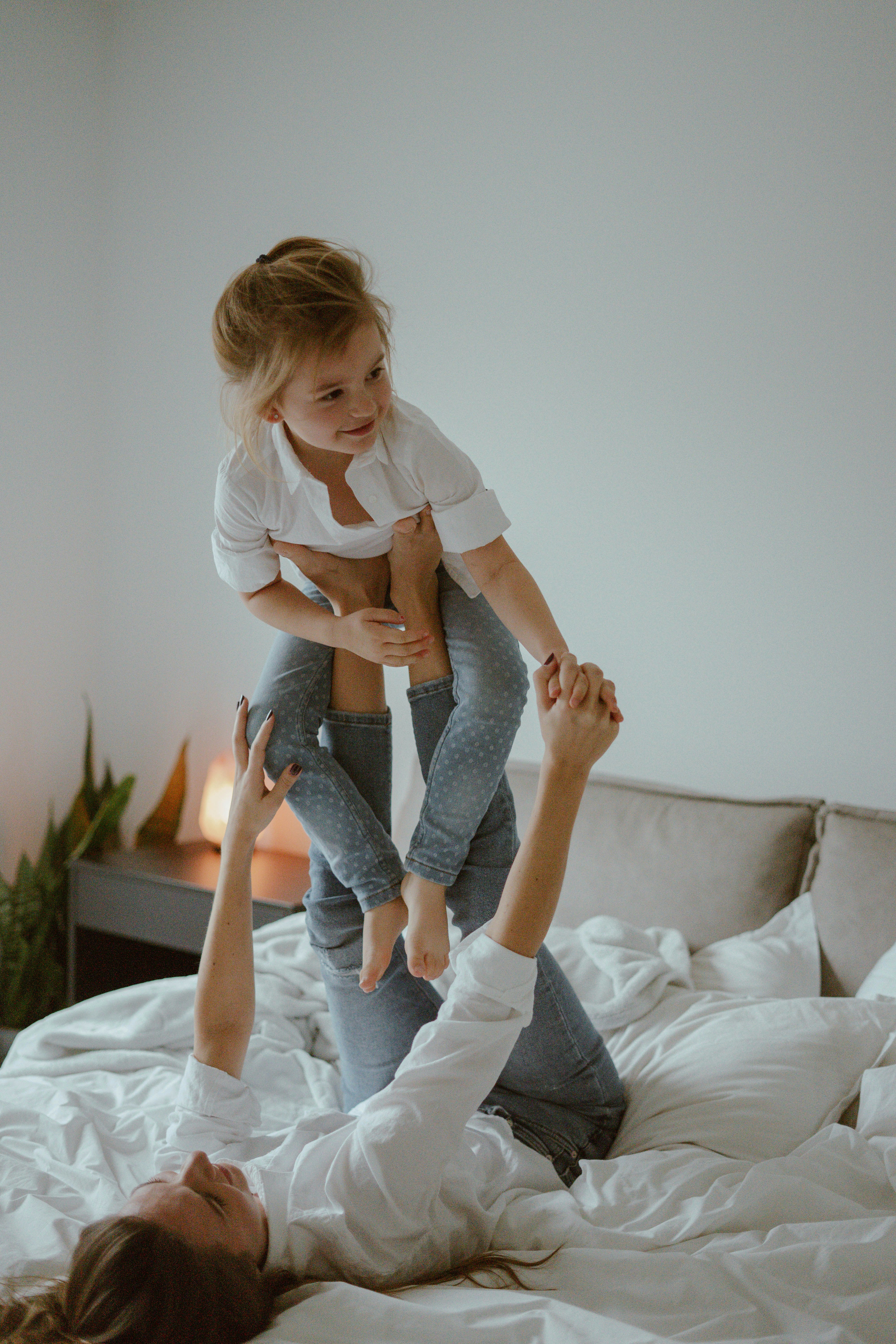 woman in white long sleeve shirt and blue denim jeans sitting on white couch